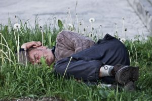 bezdomovec spí na trávniku